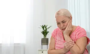Donna con mano sulla guancia, espressione sofferente, forse per una bocca urente.