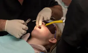 Bambina con apparecchio fisso, forse un po' di dolore nei primi giorni, mentre il dentista lavora sui suoi denti.