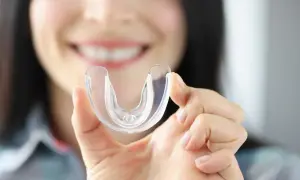 Donna sorride mostrando un bite trasparente. Scopri quanto costa un bite dal dentista per proteggere i tuoi denti.