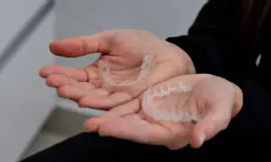 Mani che tengono bite trasparenti, utili per contrastare le mad apnee notturne.