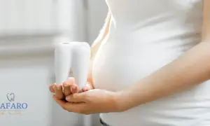 Mani di donna incinta tengono un dente bianco, simbolo della cura per la pulizia dei denti in gravidanza.