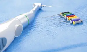 Strumenti endodontici colorati e un manipolo dentale, pronti per un trattamento di canal root sealer.