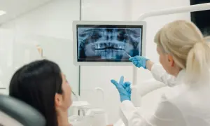 La dentista mostra una radiografia panoramica a una paziente. La visita opt dentista è in corso.