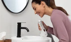 Donna sorridente impara come usare idropulsore in bagno.