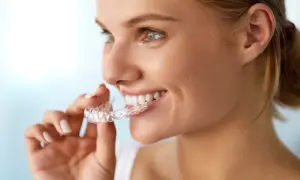 Donna sorridente mostra il suo invisalign indossato, un sorriso smagliante in arrivo.