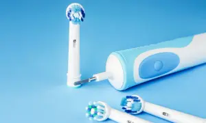 Spazzolino elettrico si accende da solo, pronto per l'igiene orale. Testine di ricambio su sfondo blu.