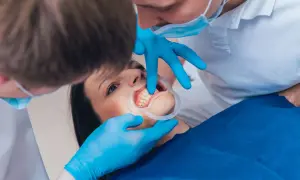 Dentista esamina i denti di una paziente, che ha un divaricatore in bocca. I mammelloni denti sono ben visibili.