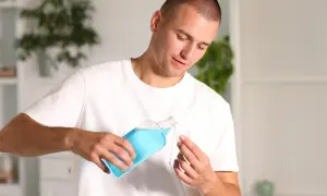 Uomo versa collutorio con clorexidina in un bicchierino.