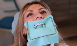 Donna con diga di gomma dentista, pronta per un trattamento.