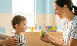 Dentista mostra un modello di dente a un bambino, spiegando l'importanza dell'ortodonzia intercettiva per un sorriso sano fin da piccoli.
