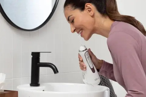 Donna sorridente impara come usare idropulsore in bagno.