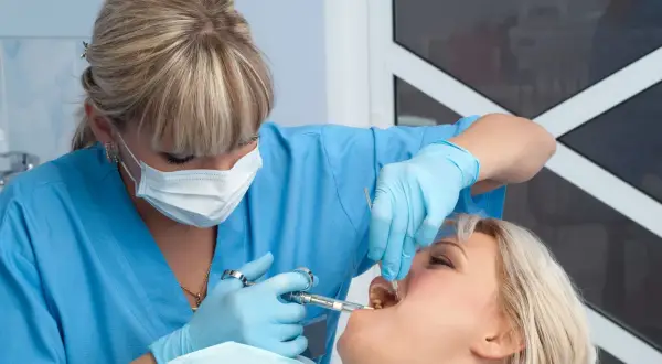 Dentista somministra anestetico per mal di denti a una paziente.