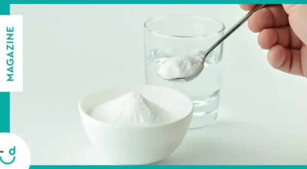 Un cucchiaino di bicarbonato pronto per essere sciolto in un bicchiere d'acqua. Un rimedio casalingo per diversi usi.