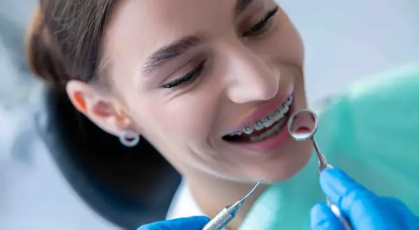 Sorriso con apparecchio ortodontico, mentre il dentista esamina i denti. Nessun mal di denti apparecchio, solo un controllo di routine.