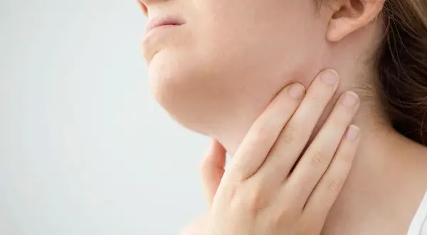 Mano che tocca il collo, forse per sentire i linfonodi sottomentali ingrossati.