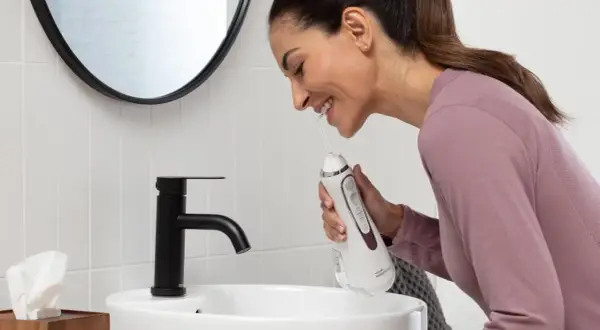 Donna sorridente impara come usare idropulsore in bagno.