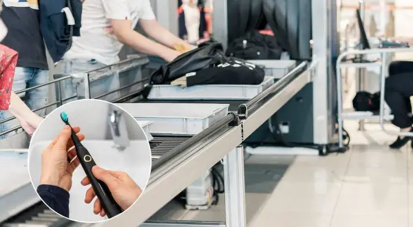 Spazzolino elettrico in aereo, pronto per essere messo nel bagaglio a mano. La sicurezza aeroportuale controlla borse e zaini.