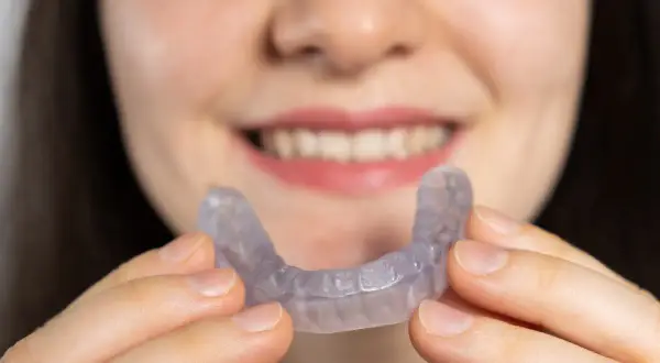 Una persona sorride mostrando un apparecchio trasparente, progettato per allineare i denti e migliorare la salute degli ossa mascellari.
