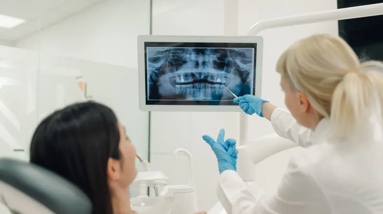 La dentista mostra una radiografia panoramica a una paziente. La visita opt dentista è in corso.