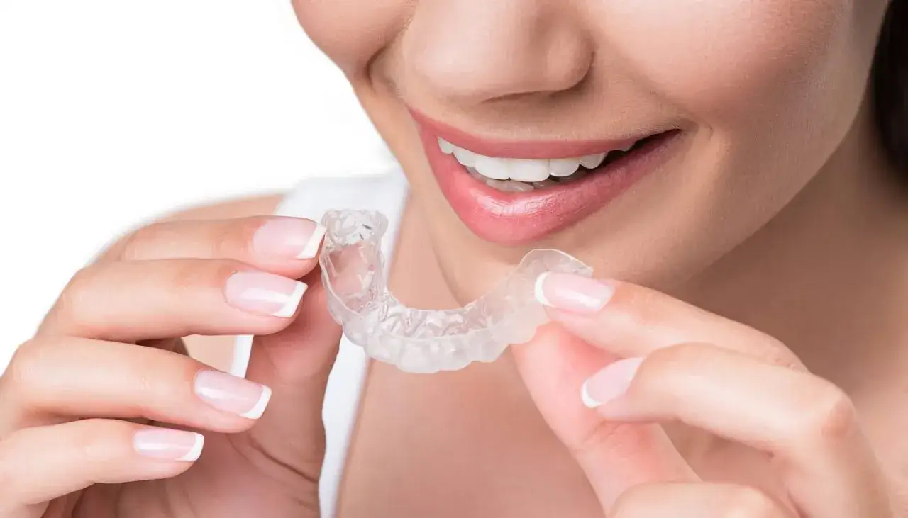 Donna sorride mostrando un bite trasparente, soluzione per il bruxismo consigliata dal dentista.