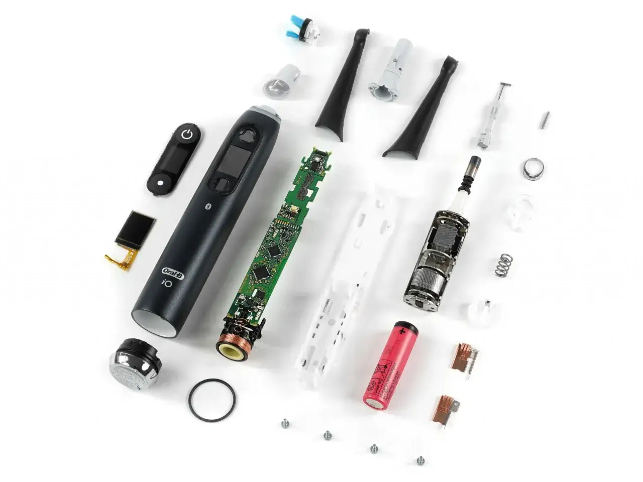 Componenti di uno spazzolino elettrico Oral-B iO smontato. La batteria e la scheda madre sono visibili, suggerendo che lo spazzolino elettrico si accende da solo.