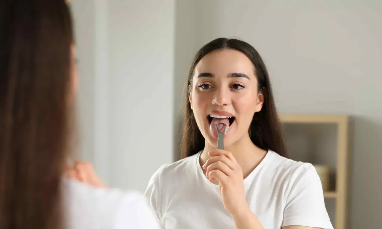 Ragazza usa un pulisci lingua per una pulizia profonda. La sua lingua sembra una lava lingua, pronta per essere purificata.