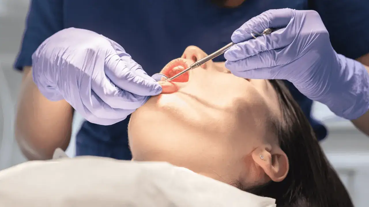 Dentista esamina la bocca di una paziente, uno strumento medico è vicino alla lingua. La biopsia lingua è dolorosa, ma necessaria per la salute.