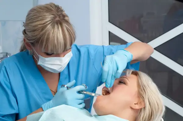 Dentista somministra anestetico per mal di denti a una paziente.