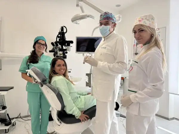 Sorrisi in clinica: un dentista, due assistenti e una paziente felice. La prima visita dal dentista si paga, ma la salute orale è un investimento.