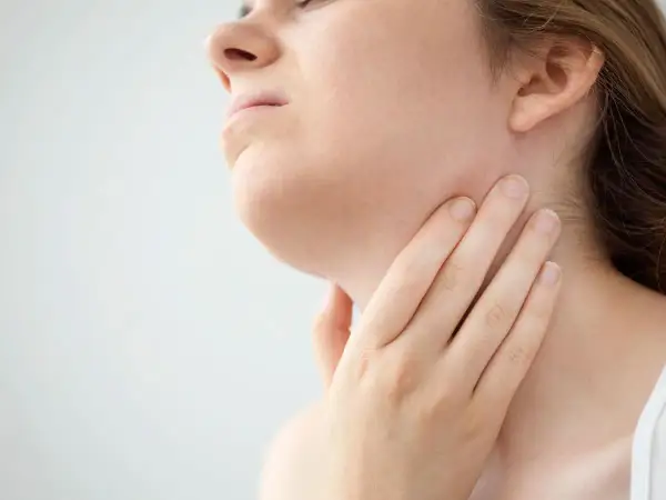 Mano che tocca il collo, forse per sentire i linfonodi sottomentali ingrossati.