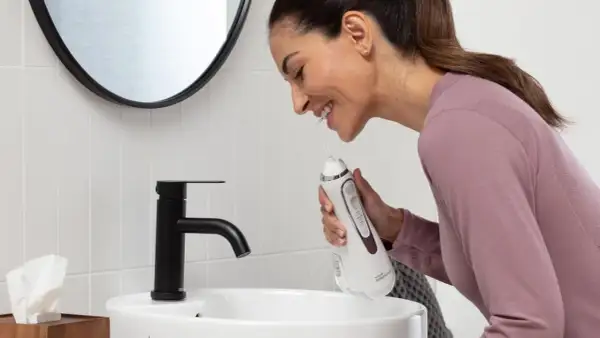 Donna sorridente impara come usare idropulsore in bagno.