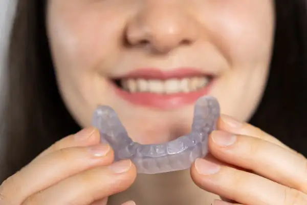 Una persona sorride mostrando un apparecchio trasparente, progettato per allineare i denti e migliorare la salute degli ossa mascellari.